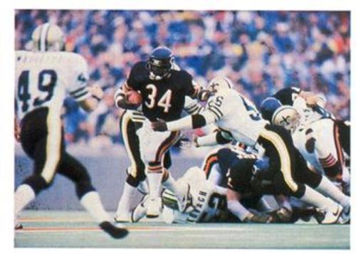 A football player in a black jersey with the number 34 runs past defenders during a game.
