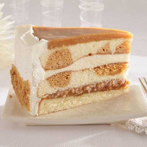 A slice of layered cake with cream, caramel, and sponge layers on a white plate.