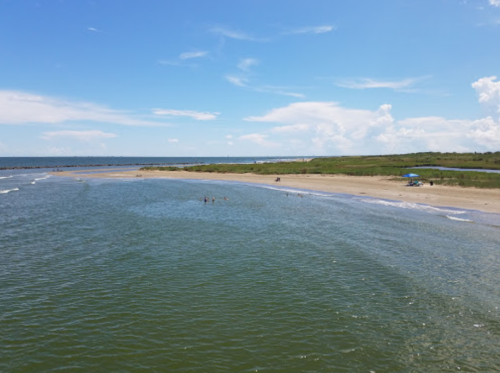 A serene beach scene with gentle waves, people enjoying the water, and a clear blue sky.
