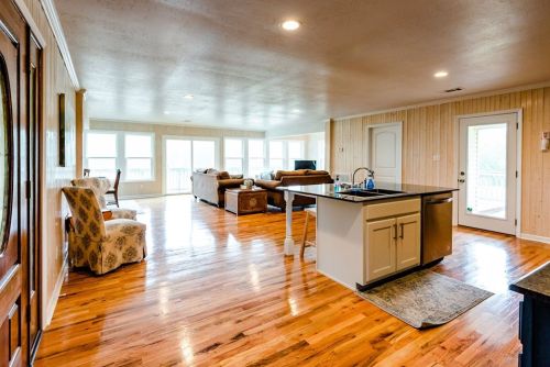 Spacious living area with hardwood floors, large windows, and a kitchen island, featuring cozy seating and natural light.