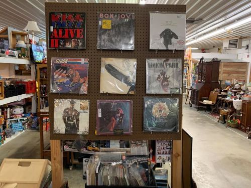 A display of vinyl records featuring artists like Kiss, Bon Jovi, and Linkin Park in a vintage store setting.