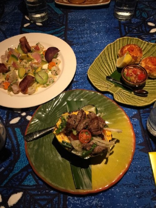 A colorful table setting with three dishes: a salad, grilled meat with vegetables, and stuffed pastries, all on vibrant plates.