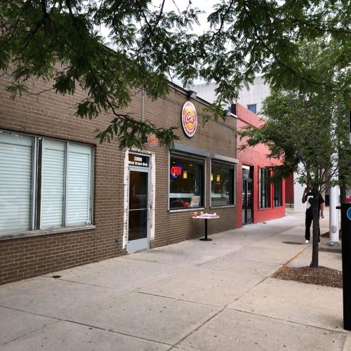 Exterior view of a restaurant with a sign that says "OPEN," surrounded by trees and a sidewalk.