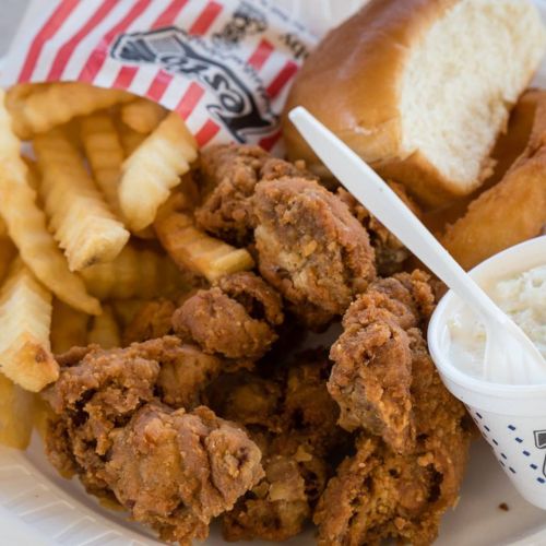A plate of crispy fried chicken, crinkle-cut fries, a soft bun, and a side of coleslaw.