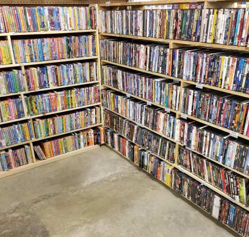 A corner of a room filled with shelves stacked with various DVDs and Blu-rays in colorful cases.