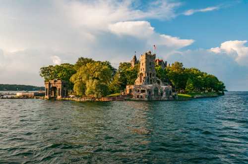 A scenic view of a castle on an island surrounded by water, with lush trees and a blue sky in the background.