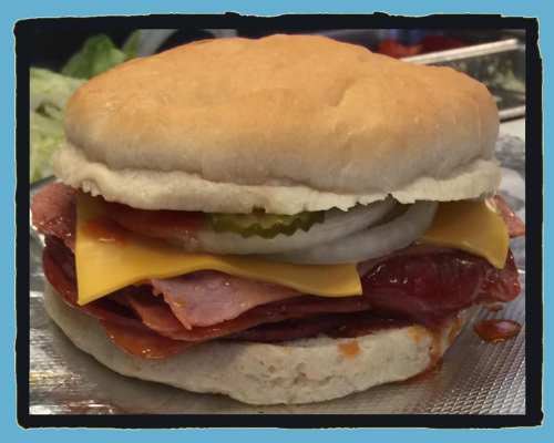 A hearty sandwich with layers of ham, cheese, pickles, and onions, all nestled in a soft bun.