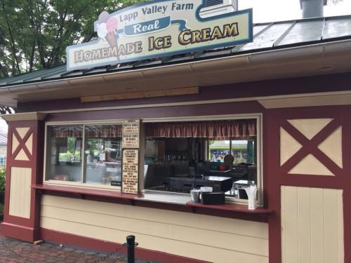 A quaint ice cream stand with a sign reading "Lapp Valley Farm Real Homemade Ice Cream" and a menu displayed.