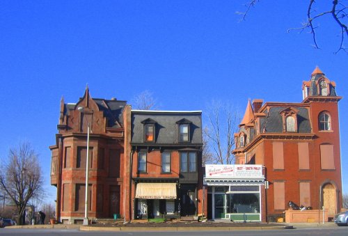 Three historic buildings with distinct architectural styles, set against a clear blue sky.
