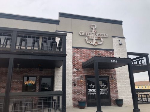 Exterior of Tropicana Bar & Grill, featuring a brick facade and a large anchor sign, with outdoor seating visible.