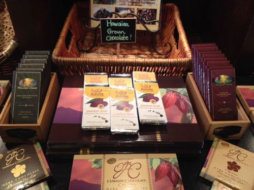 Display of various chocolate bars, including Hawaiian grown chocolate and passion fruit flavors, in a cozy shop setting.