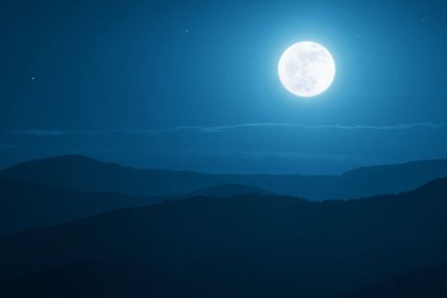 A bright full moon illuminates a serene night sky over dark, rolling mountains. Stars twinkle in the background.