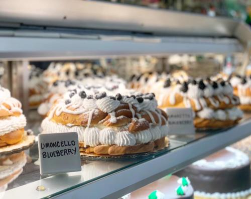 A display case filled with beautifully decorated cakes, including limoncello blueberry and other flavors.