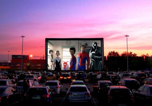 A drive-in theater at sunset shows animated characters, including Spider-Man, on a large screen with parked cars in front.
