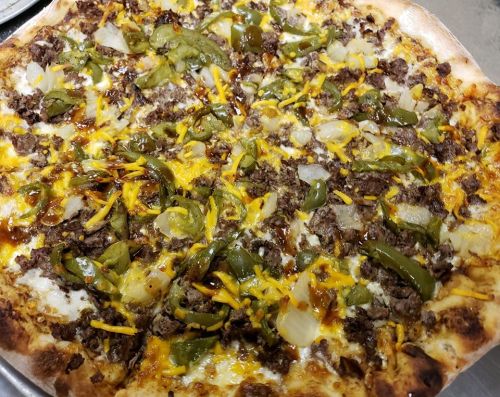 A close-up of a pizza topped with ground beef, green peppers, onions, and shredded cheese on a golden crust.