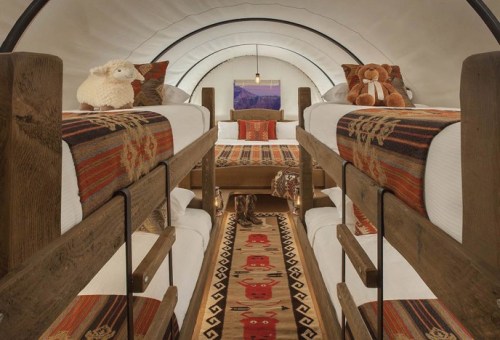 Cozy interior of a cabin with bunk beds, colorful rugs, and plush toys, creating a warm, inviting atmosphere.