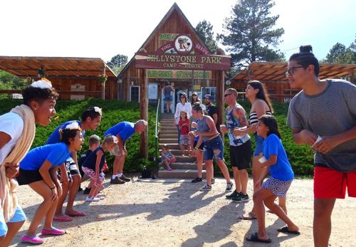 A group of people in colorful outfits preparing for a fun activity outside the entrance of Jellystone Park Camp Resort.