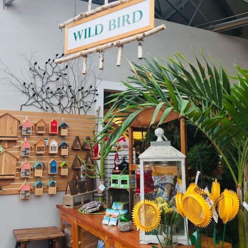 A display featuring birdhouses, bird feeders, and sunflower decorations in a shop labeled "Wild Bird."