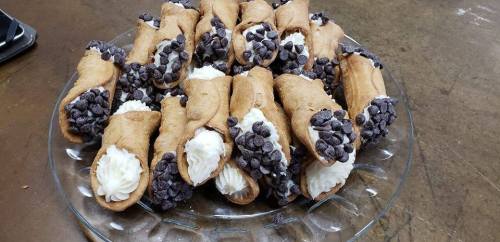 A plate of cannoli filled with cream and topped with chocolate chips, arranged neatly.