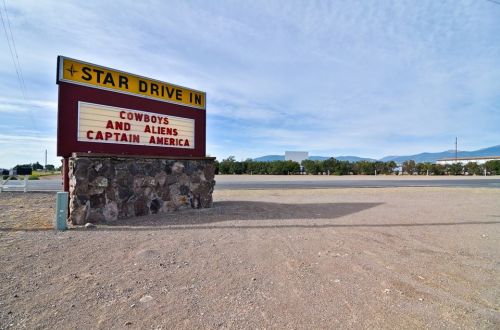 Sign for Star Drive-In featuring movie titles "Cowboys and Aliens" and "Captain America," with a clear sky in the background.