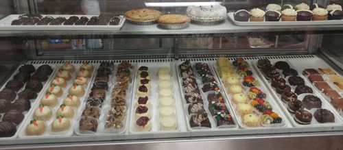 A display case filled with various desserts, including cupcakes, cookies, and chocolate treats.