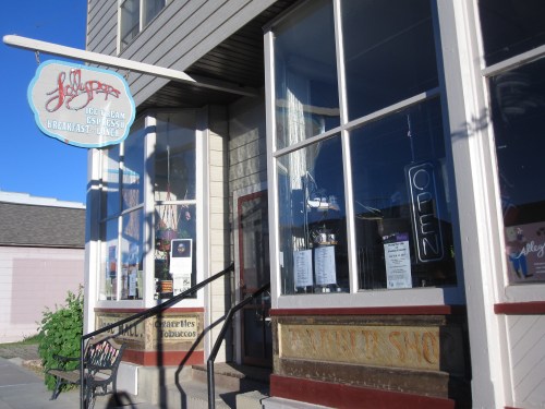 A quaint ice cream shop with a blue sign, large windows, and an "OPEN" sign, showcasing a welcoming atmosphere.