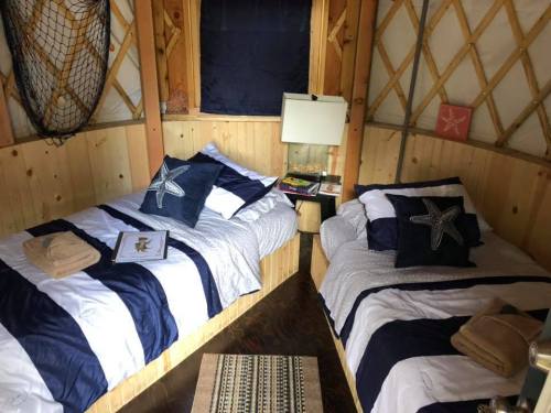Cozy yurt interior with two twin beds, nautical decor, and a small bedside table.