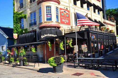 Exterior of Sobelman's restaurant with an American flag, planters, and outdoor seating on a sunny day.