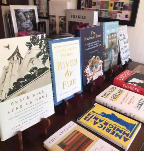 A display of various books on a table, featuring titles like "Grace Will Lead Us Home" and "River of Fire."