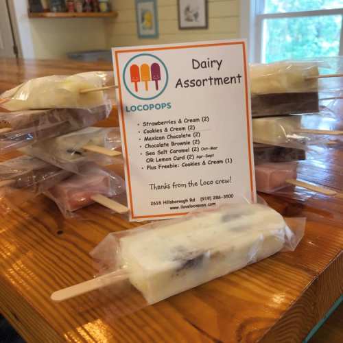 A variety of frozen treats in clear packaging, with a sign listing flavors and thanking customers from Locopops.