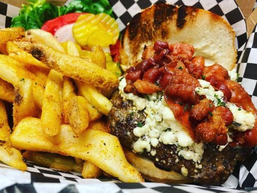 A juicy burger topped with blue cheese and bacon, served with crispy fries and fresh lettuce, tomato, and pickles.