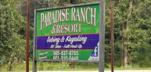 Sign for Paradise Ranch & Resort, featuring tubing, kayaking, and RV site information. Contact numbers included.
