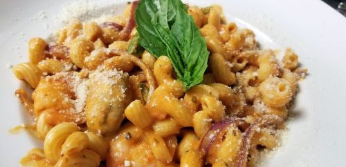 A plate of pasta with a creamy sauce, garnished with fresh basil and sprinkled with grated cheese.