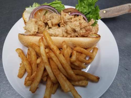 A plate featuring a fried chicken sandwich with lettuce, tomato, and onion, served with a side of golden fries.