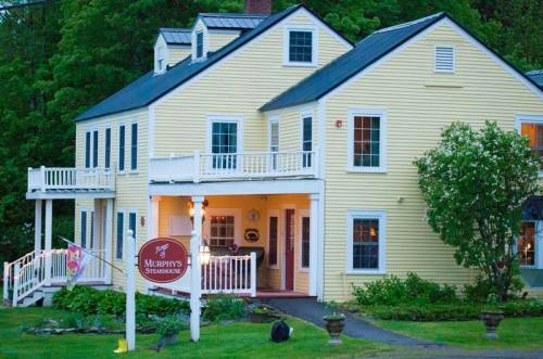 A charming yellow house with a sign for Murphy's Steakhouse, surrounded by greenery and a welcoming entrance.