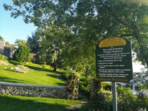 A lush garden with a sign indicating private property and rules for preserving the environment.