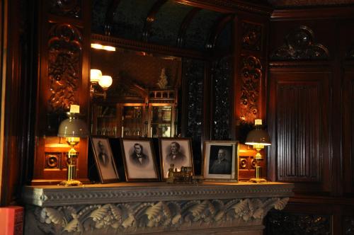 A wooden mantel with framed portraits, lamps, and a mirror reflecting a richly decorated room.