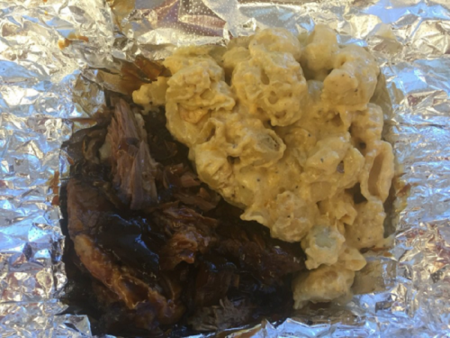 A foil container with tender pulled pork and creamy macaroni and cheese.