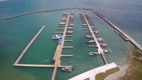 Aerial view of a marina with multiple boats docked along wooden piers in turquoise waters.