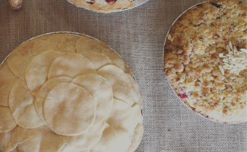 Two delicious pies on a textured surface: one with a decorative crust and another topped with crumbs and almonds.