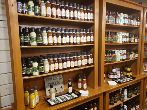 Shelves filled with various sauces and condiments, labeled and organized, with a sign reading "Grillin' & Chillin'."
