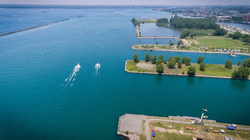 Aerial view of a blue waterway with boats, green parks, and a shoreline in a coastal city.