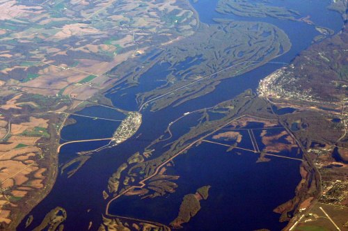 Aerial view of winding rivers and lush green landscapes, with a small town visible near the water's edge.