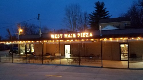 Exterior of West Main Pizza at dusk, featuring string lights and outdoor seating.
