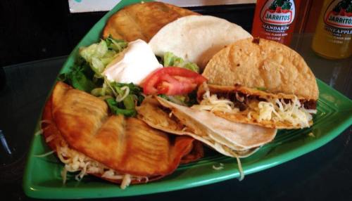 A vibrant plate of tacos, including crispy and soft varieties, served with lettuce, tomato, and sour cream.