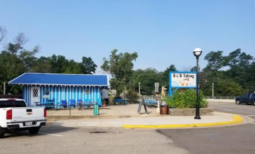 A blue-striped building with a sign for S & B Tubing, surrounded by trees and parked cars on a sunny day.