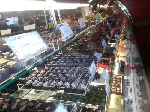 A display case filled with various chocolates and confections, labeled with names and descriptions.