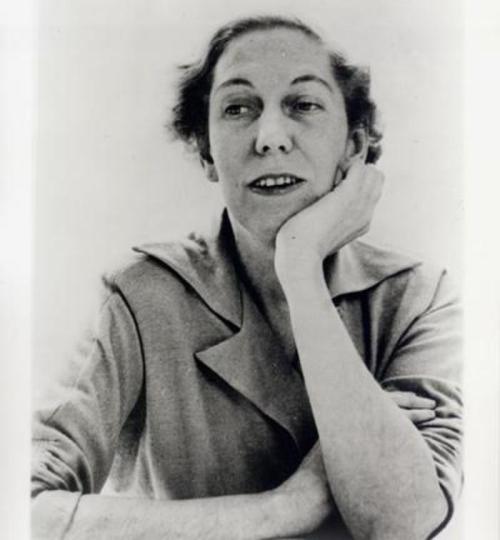 A black and white portrait of a woman resting her chin on her hand, looking thoughtfully at the camera.