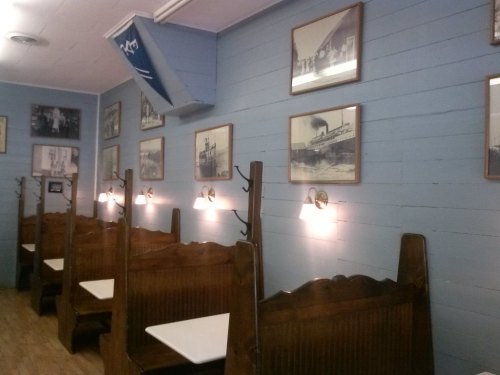 Interior of a cozy restaurant with wooden booths, blue walls, and vintage photos hanging on the walls.