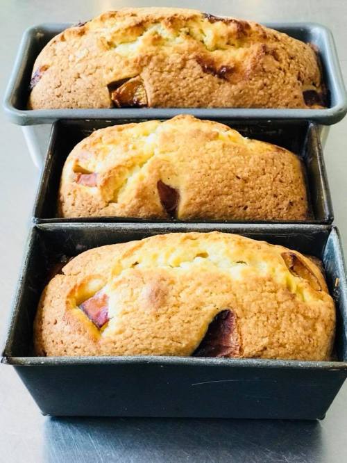 Three freshly baked loaves of bread in metal pans, with a golden-brown crust and a soft, fluffy interior.